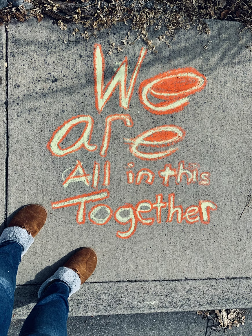 Image of "We are all in this together" written on the sidewalk